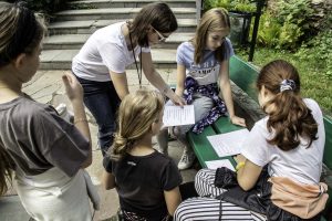 Grupa dzieci w muzealnym ogrodzie podczas gry terenowej - znajdź skarb - oferta wakacyjna